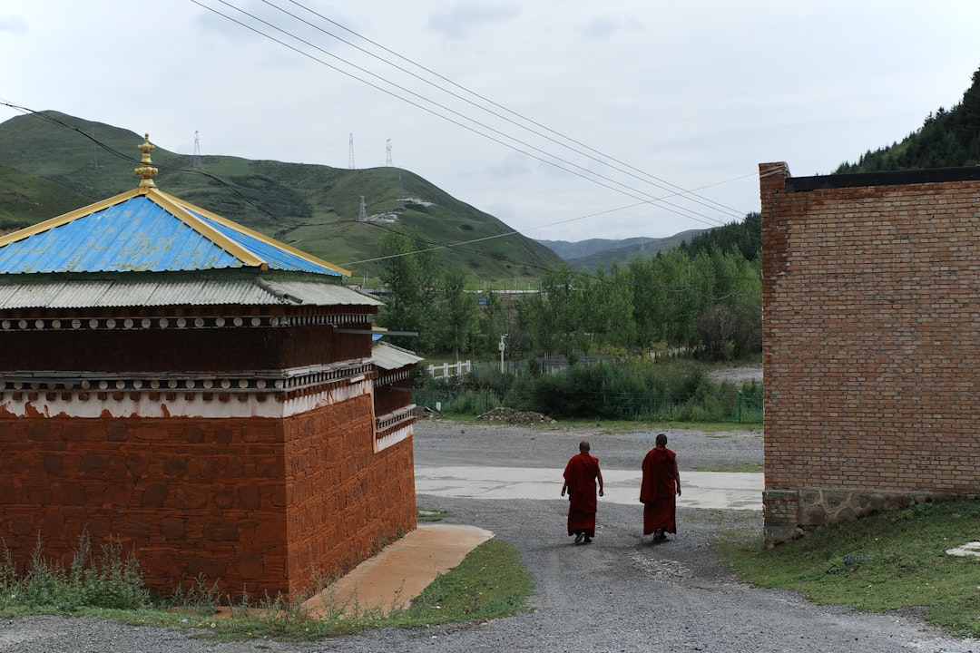Two monks walk towards a building in a valley.