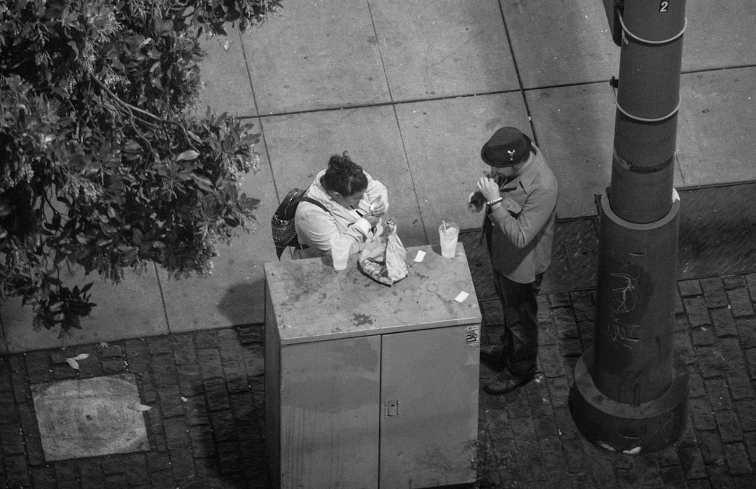 grayscale photo of woman and man standing near tre