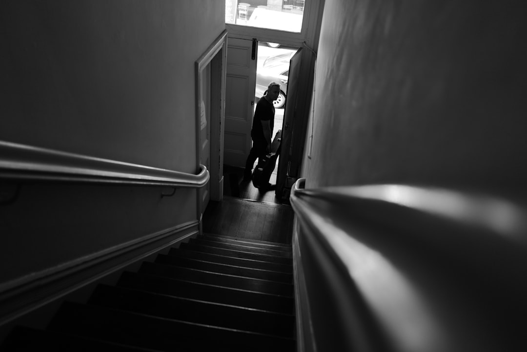 Person walking down dark stairs with railing.
