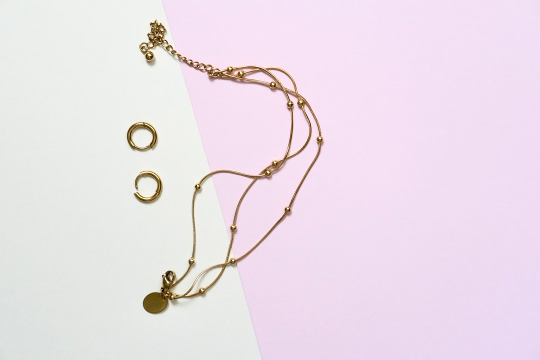 Gold necklace and earrings on pastel background.